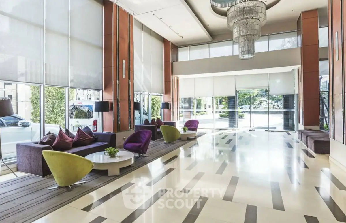 Luxurious modern lobby with elegant seating and grand chandelier in a high-end building.