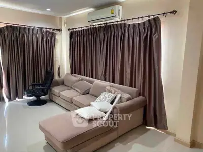 Spacious living room with plush sofa and elegant curtains, perfect for relaxation and entertainment.