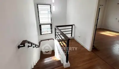 Bright staircase with wooden flooring and modern railing in a contemporary home.