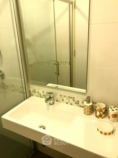 Modern bathroom with sleek sink and large mirror in stylish apartment.