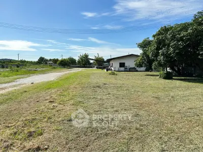 Spacious rural property with expansive lawn and charming house under clear blue sky.