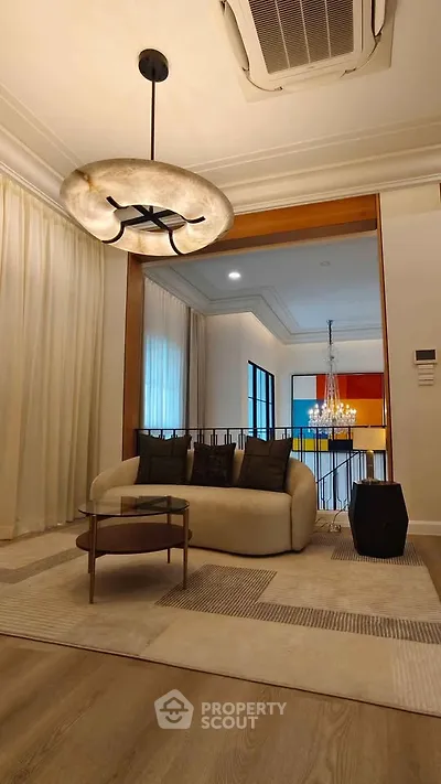 Elegant living room with modern chandelier and cozy seating area, perfect for relaxation and entertaining.
