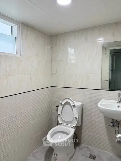 Modern bathroom with sleek tiles and compact fixtures, perfect for urban living.