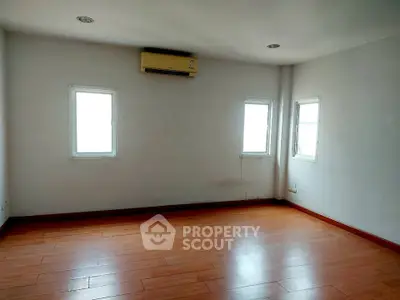 Spacious empty room with wooden flooring and air conditioning, ideal for customization.