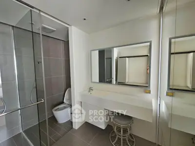Modern bathroom with glass shower and sleek vanity in contemporary apartment.