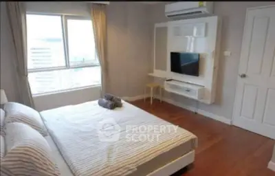 Modern bedroom with large window and wall-mounted TV in a stylish apartment.