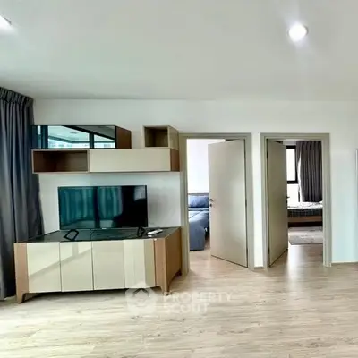 Modern living room with sleek TV stand and open bedroom doors