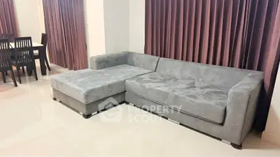 Spacious living room with modern gray sectional sofa and elegant dining area.