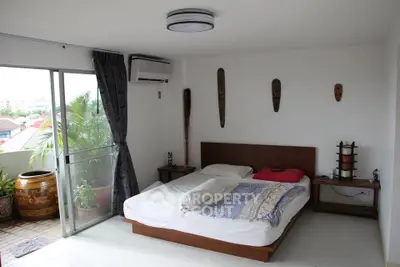 Cozy bedroom with balcony access and decorative wall masks, perfect for relaxation.