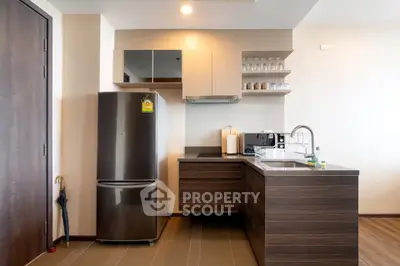 Modern kitchen with sleek cabinetry and stainless steel fridge in a stylish apartment.
