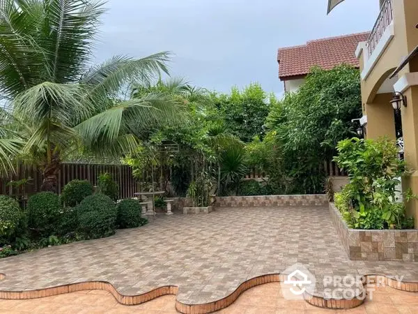 Lush tropical garden with patterned paving and mature palm trees enhancing the serene outdoor space of a luxurious residence.