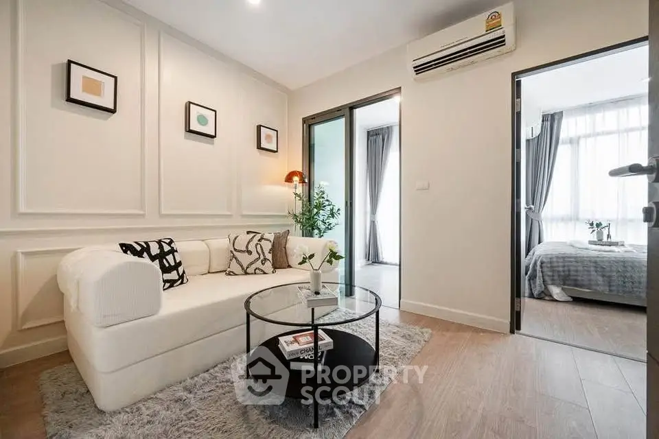 Modern living room with cozy sofa and stylish decor leading to a bright bedroom.