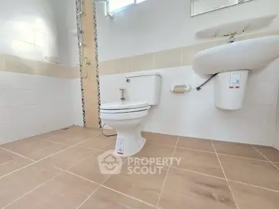 Modern bathroom with sleek fixtures and tiled flooring, featuring a shower and toilet.