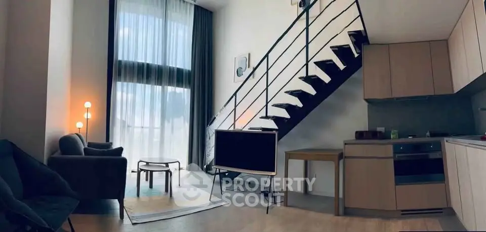 Modern loft apartment with high ceilings, stylish staircase, and open kitchen layout.
