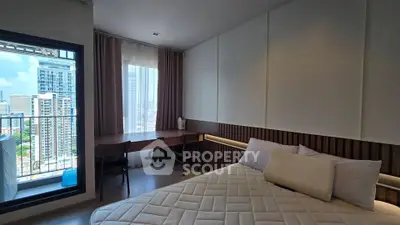 Modern bedroom with city view and balcony access in high-rise apartment
