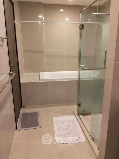 Modern bathroom with sleek glass shower and built-in bathtub in a contemporary apartment.