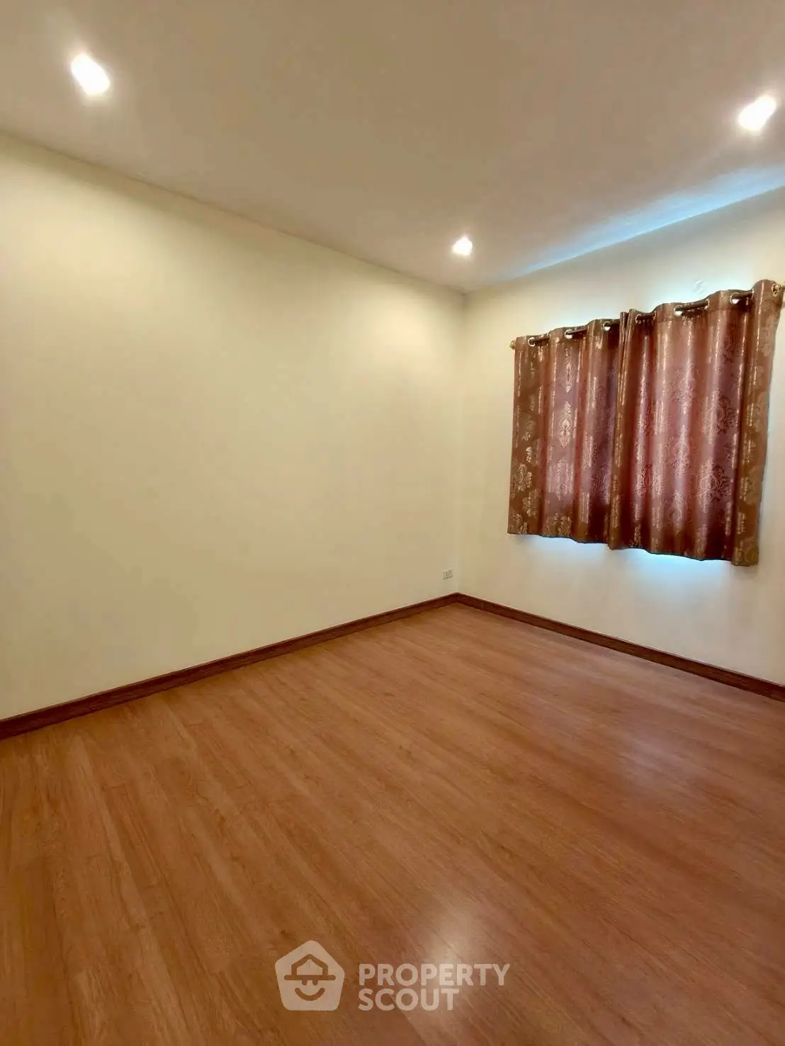 Spacious empty room with wooden flooring and elegant curtains, perfect for customization.