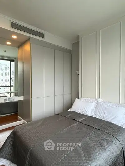 Modern bedroom with city view, featuring sleek built-in wardrobe and cozy bedding.