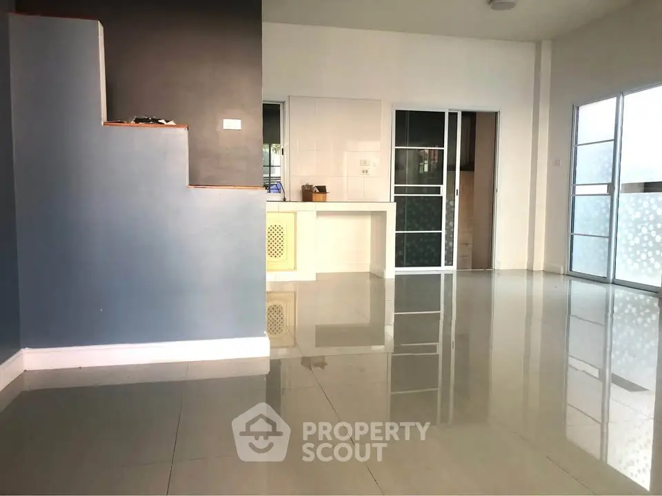 Spacious modern living room with glossy tiled floors and large windows for natural light.