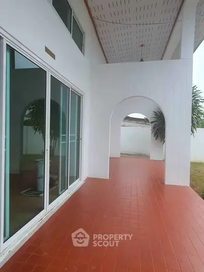 Spacious covered patio with red tile flooring and sliding glass doors