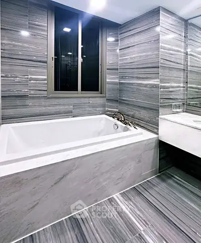 Luxurious modern bathroom with elegant marble tiles and spacious bathtub.