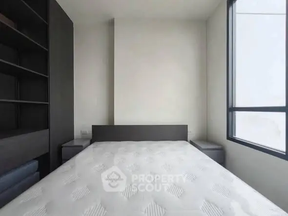 Modern minimalist bedroom with large window and built-in shelving.