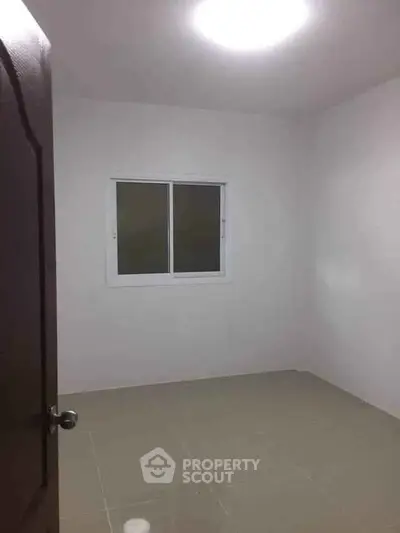 Minimalist empty room with tiled floor and window, ideal for customization.