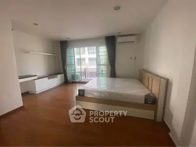 Spacious bedroom with wooden flooring and large window in modern apartment