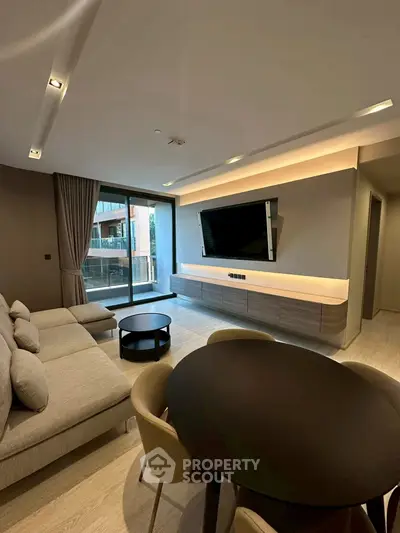 Modern living room with sleek furniture and large TV, featuring a spacious balcony view.