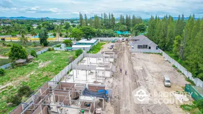 Aerial view of residential construction site with lush greenery and scenic surroundings.