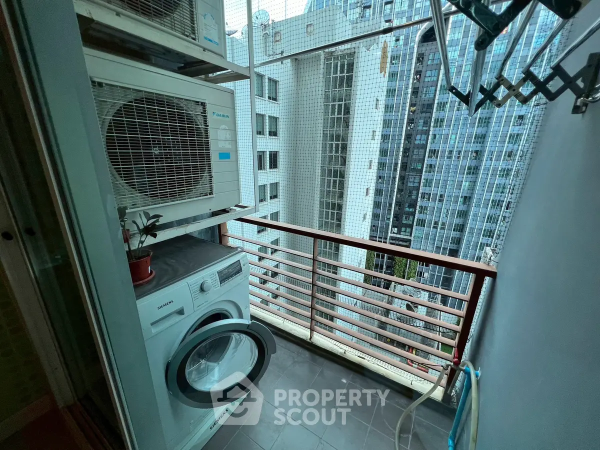 Compact balcony with washing machine and city view, ideal for urban living.