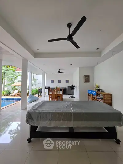 Spacious open-plan living area with pool view and modern furnishings, perfect for relaxation and entertainment.
