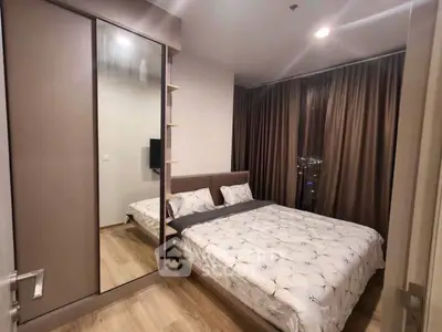 Cozy bedroom with modern decor and large mirrored wardrobe in a stylish apartment.
