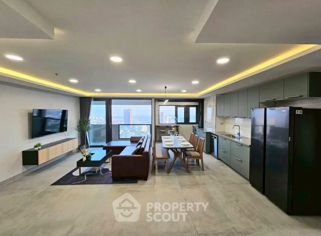 Spacious open-layout living room with modern kitchen and stunning city view.