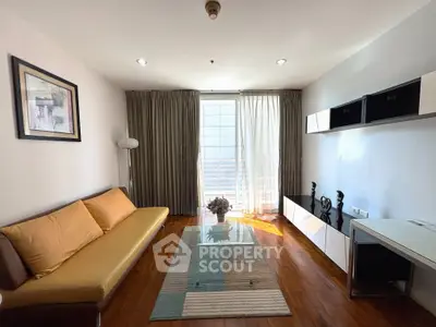 Modern living room with stylish decor, wooden flooring, and ample natural light from large windows.