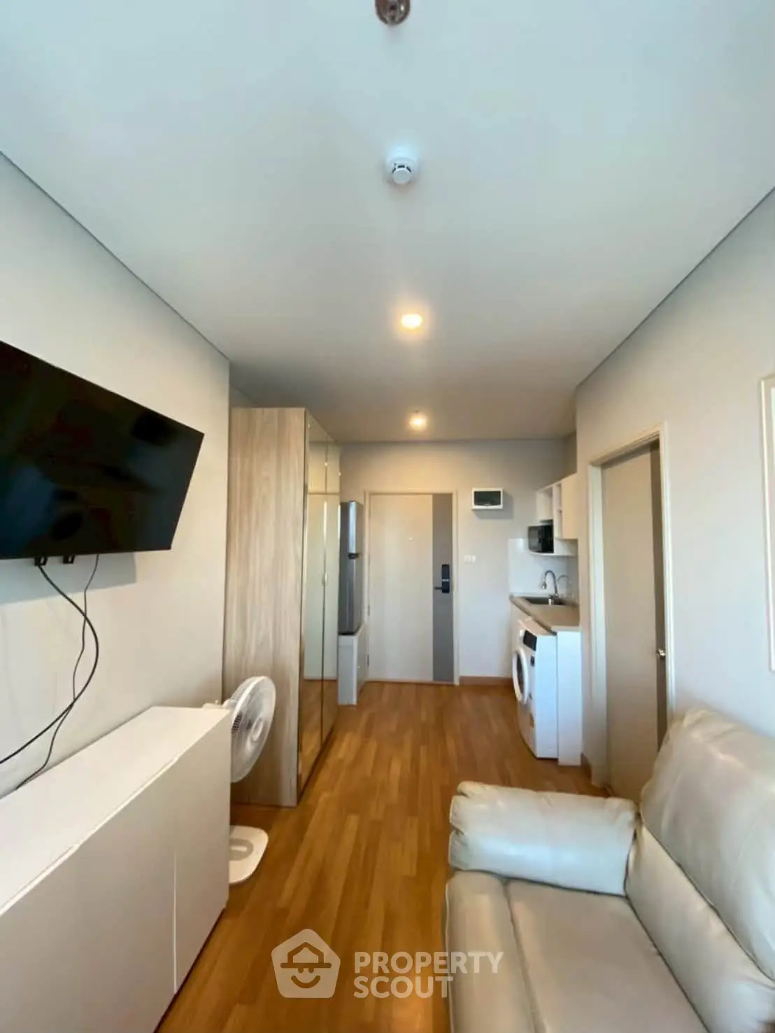 Modern living room with sleek furniture and built-in appliances in a cozy apartment.