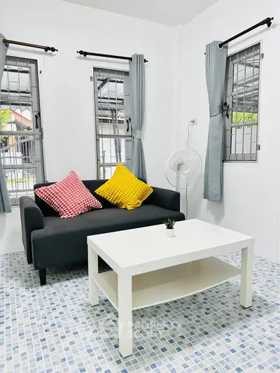 Charming living room with cozy sofa, vibrant cushions, and stylish coffee table in bright, airy space.