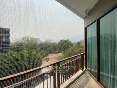 Spacious balcony with scenic view of lush greenery and distant mountains, perfect for relaxation.