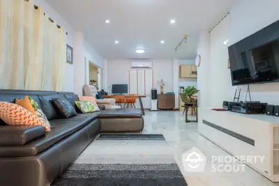 Spacious and modern living room with plush leather sofa, sleek entertainment unit, and tasteful decor, illuminated by ample recessed lighting.