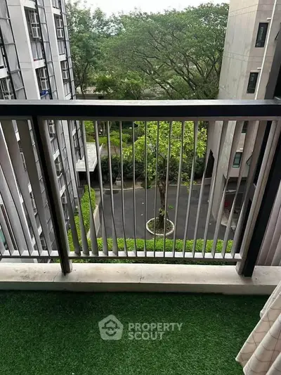 Charming balcony view with lush greenery and modern building exterior, perfect for relaxation.