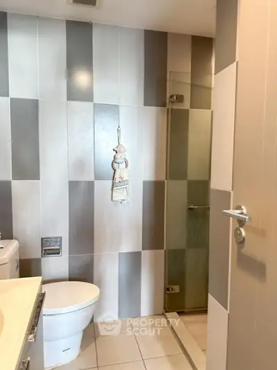 Modern bathroom with stylish striped tiles and glass shower door