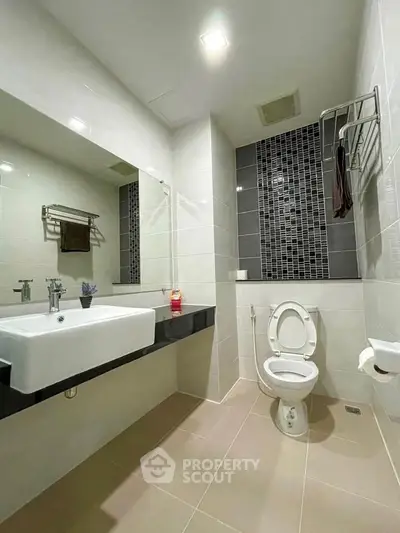 Modern bathroom with sleek design, featuring a large mirror and contemporary fixtures.