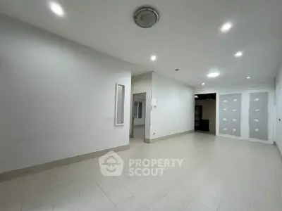 Spacious unfurnished room with tiled flooring and recessed lighting, ideal for customization.