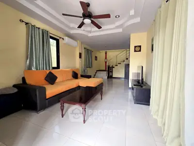 Spacious living room with modern furniture and ceiling fan in a stylish home.