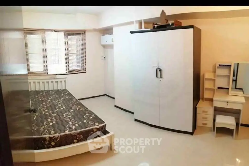 Spacious bedroom with large wardrobe and natural light from windows.