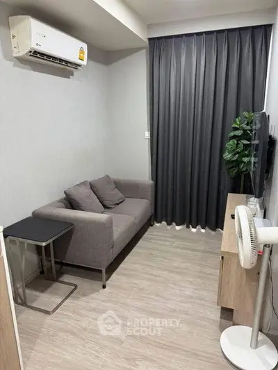 Cozy living room with modern sofa, air conditioning, and stylish decor in a compact apartment.