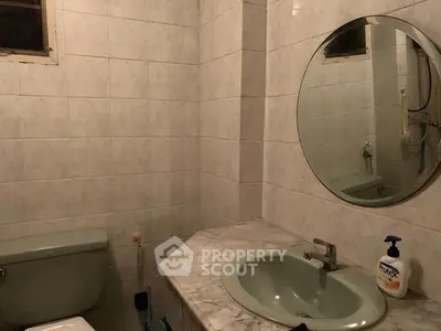 Cozy bathroom with vintage green fixtures and round mirror