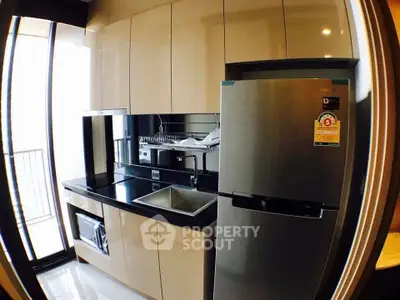 Modern kitchen with sleek cabinets and stainless steel fridge in a compact layout.