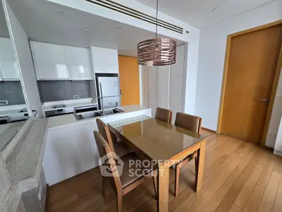 Modern kitchen with dining area featuring sleek cabinetry and wooden flooring.