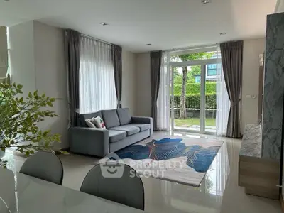 Spacious living room with modern decor and large windows overlooking garden.